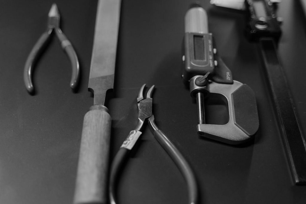 Monochrome image featuring various workshop tools arranged neatly on a surface.